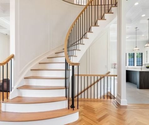 A curved staircase with wooden steps and a metal railing in a house.