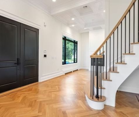 A hallway with wooden floors and stairs in a house.