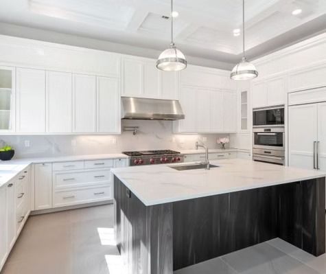 A kitchen with white cabinets , stainless steel appliances , and a large island.