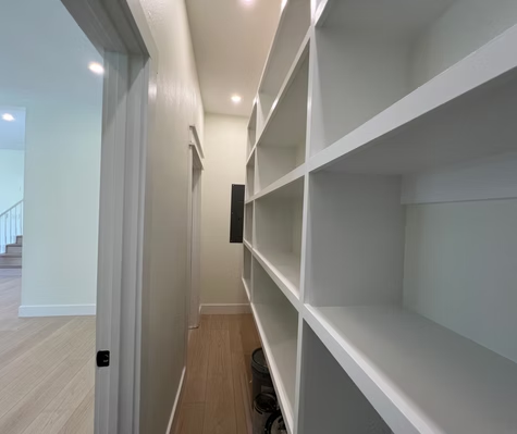 A walk in closet with lots of shelves in a house.