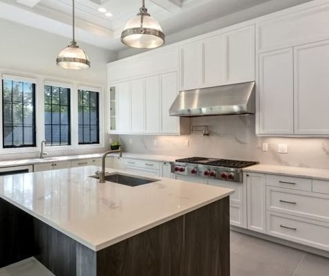 A kitchen with white cabinets , stainless steel appliances , and a large island.