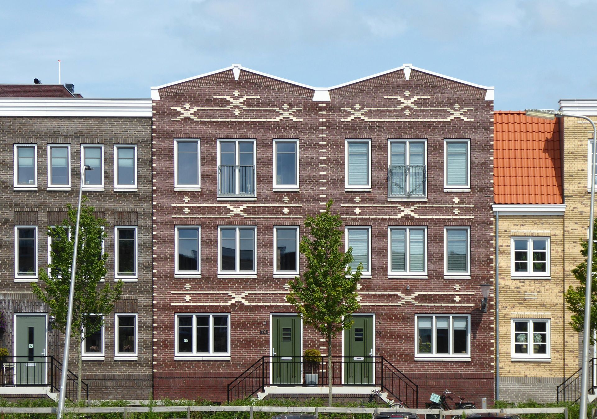 Two-story white building with green window trim, a white door, and overhead wires against a blue sky.