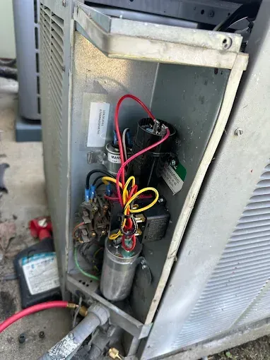 Open AC unit showing electrical components with wires.
