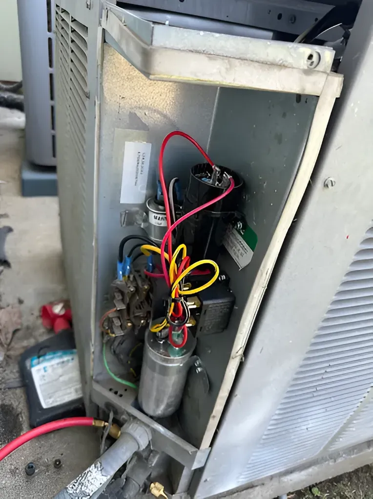 Open AC unit with wires and capacitors. Metal housing.