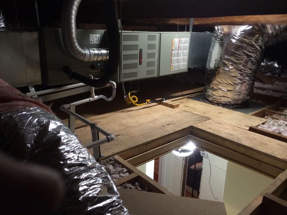 Attic with HVAC system, ductwork, and wooden flooring around an access opening.