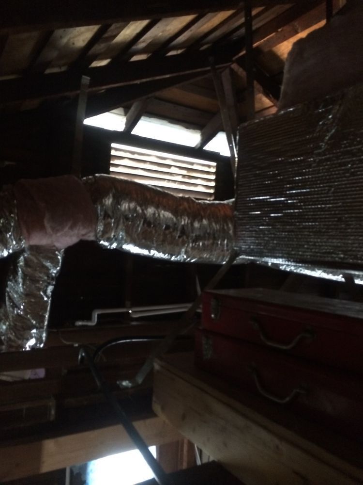 Attic interior with ductwork, insulation, and a red toolbox.