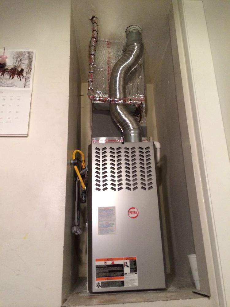 Furnace installed in a recessed wall cavity. Silver metal unit, ductwork, copper piping, and calendar.