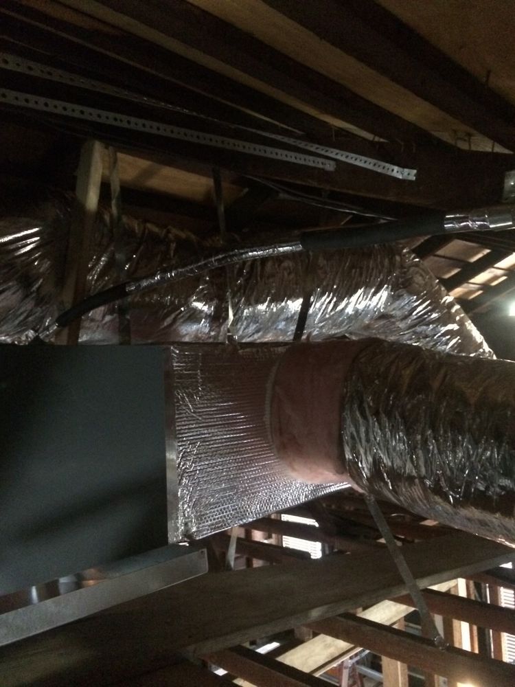 Attic with HVAC ductwork, gray metal, silver insulated flexible ducts, and wooden beams.