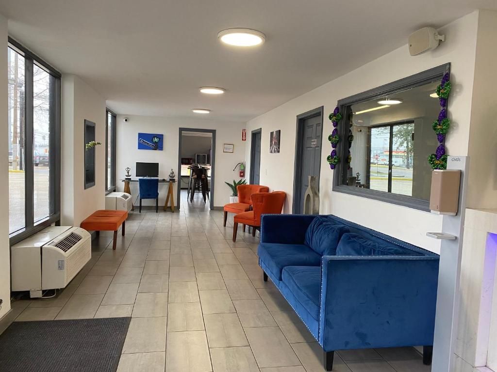 Hotel lobby with blue couch, orange chairs, and a large mirror.