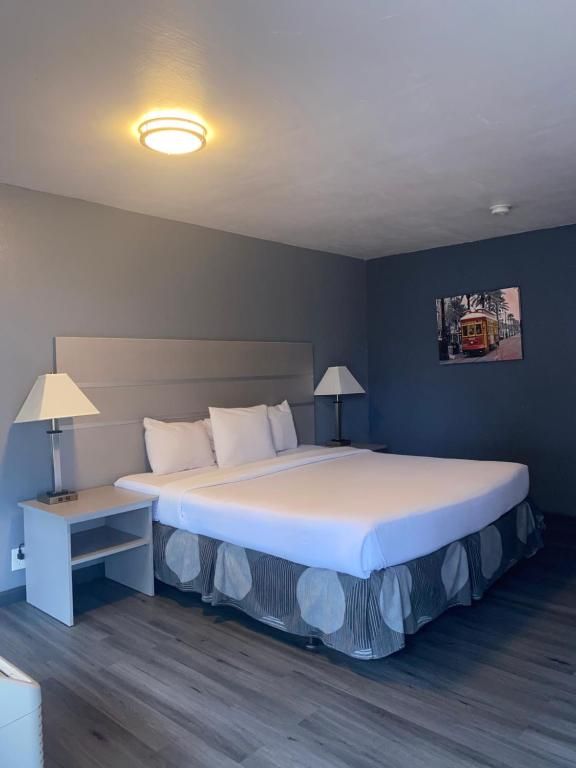 Hotel room with king-size bed, gray walls, bedside tables, lamps, and art of a cable car.