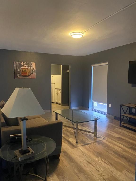 Living room with grey walls, brown couch, glass coffee table, and light wooden floor.