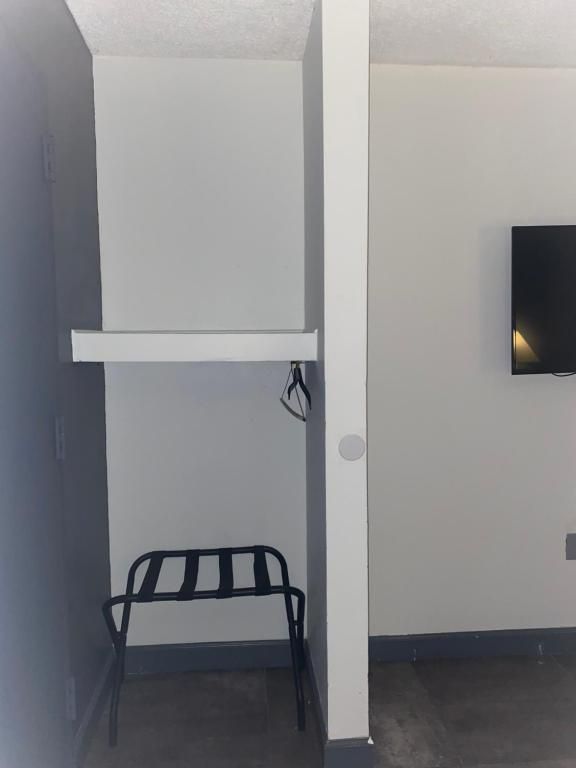 A built-in closet area with a shelf, luggage rack, and hanging rod. Gray and white walls.