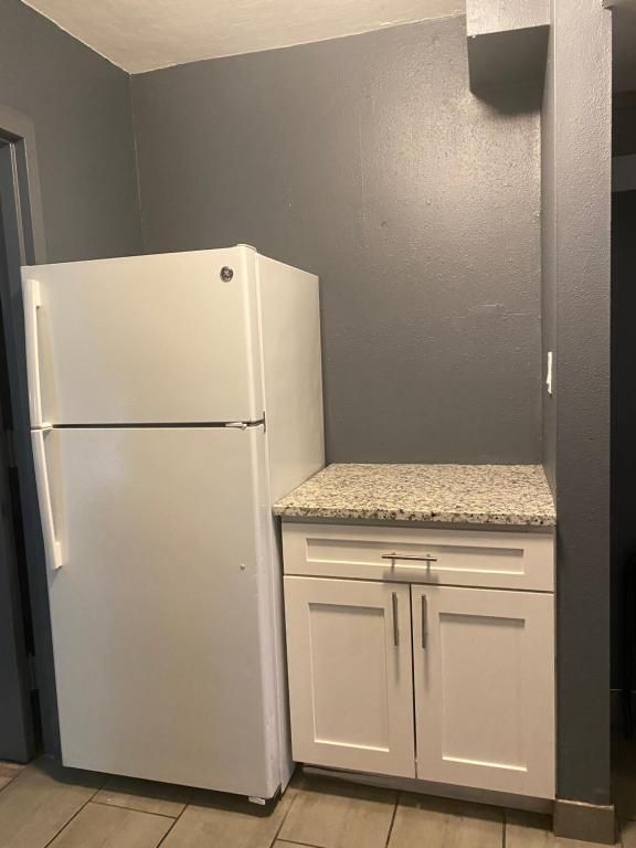 White refrigerator and cabinet next to each other against a gray wall.