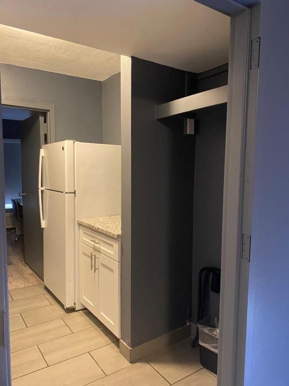 Kitchenette with white appliances, gray walls, and light-colored tile flooring.