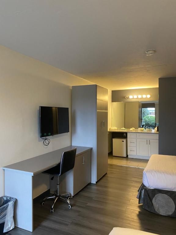 Hotel room with desk, TV, closet, and two beds. Gray and white color scheme.