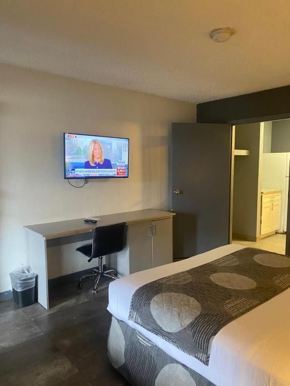 Hotel room with a bed, desk, TV, and open doorway to bathroom.