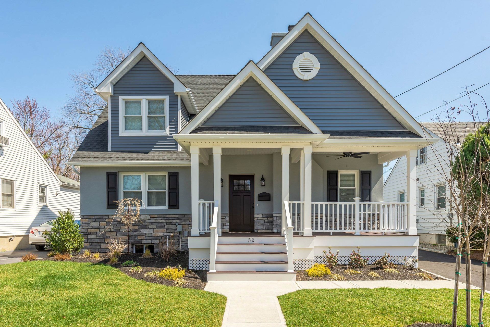 A gray and white house with a porch and a walkway.