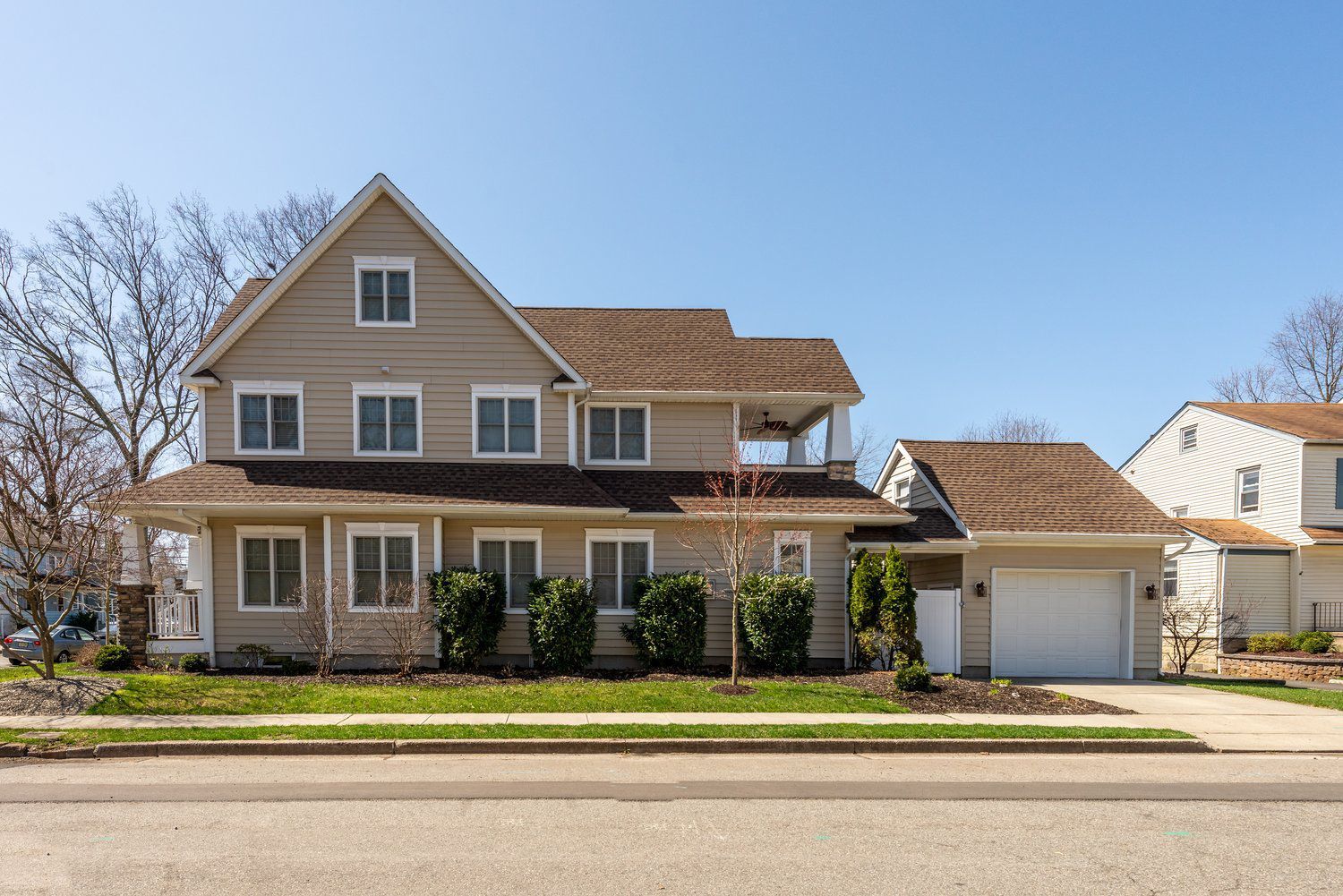A large house with a white garage door is sitting on the side of the road.