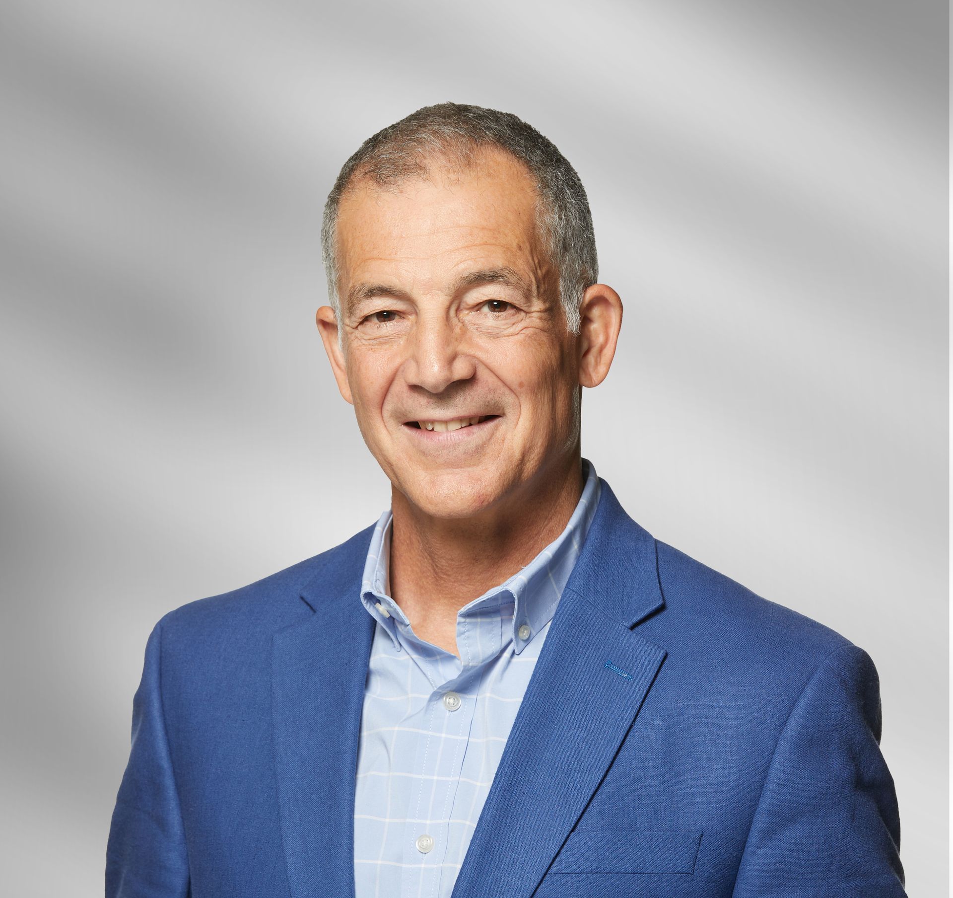 A man in a blue suit and blue shirt is smiling for the camera.