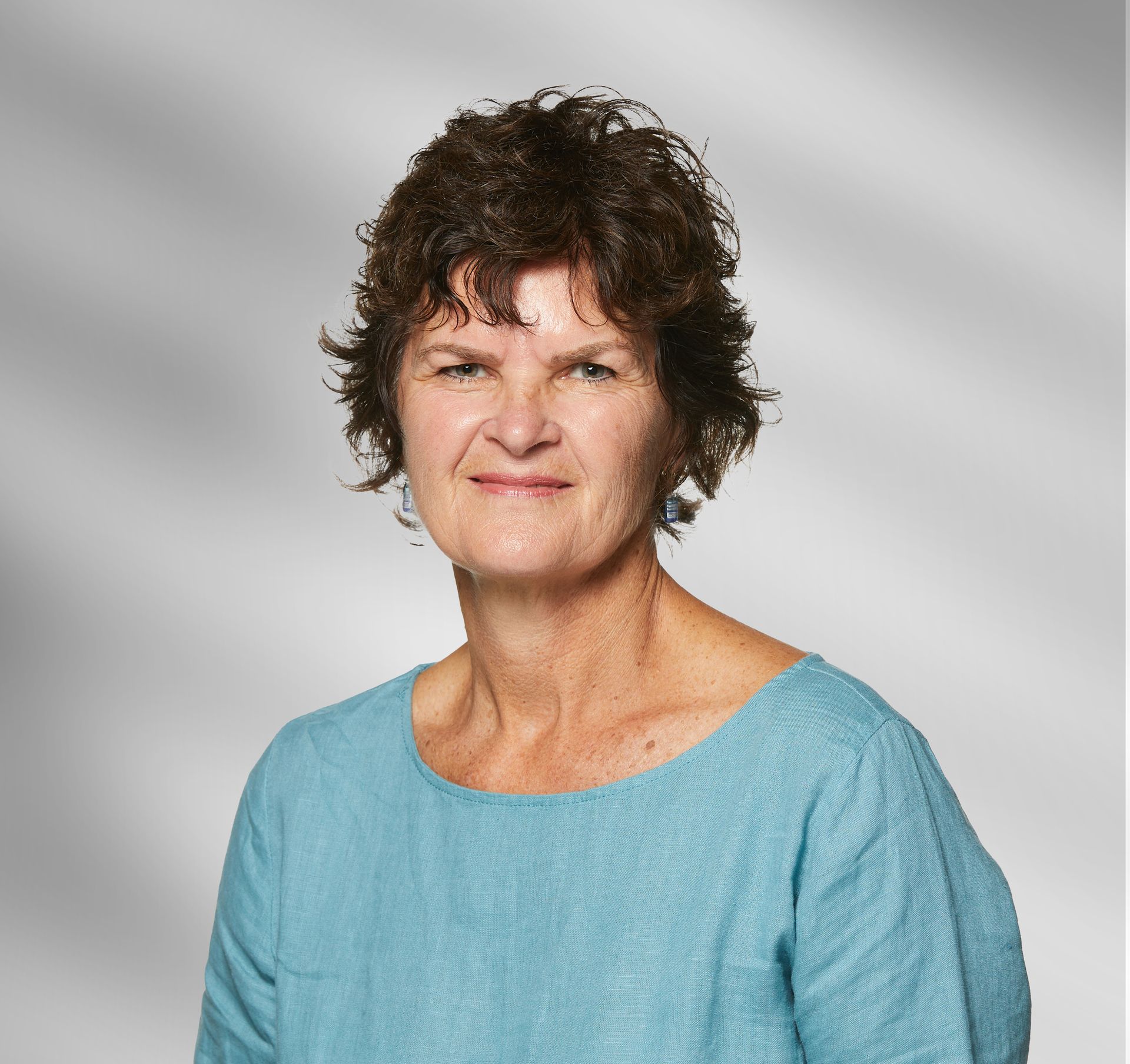 A woman in a blue shirt is smiling for the camera.