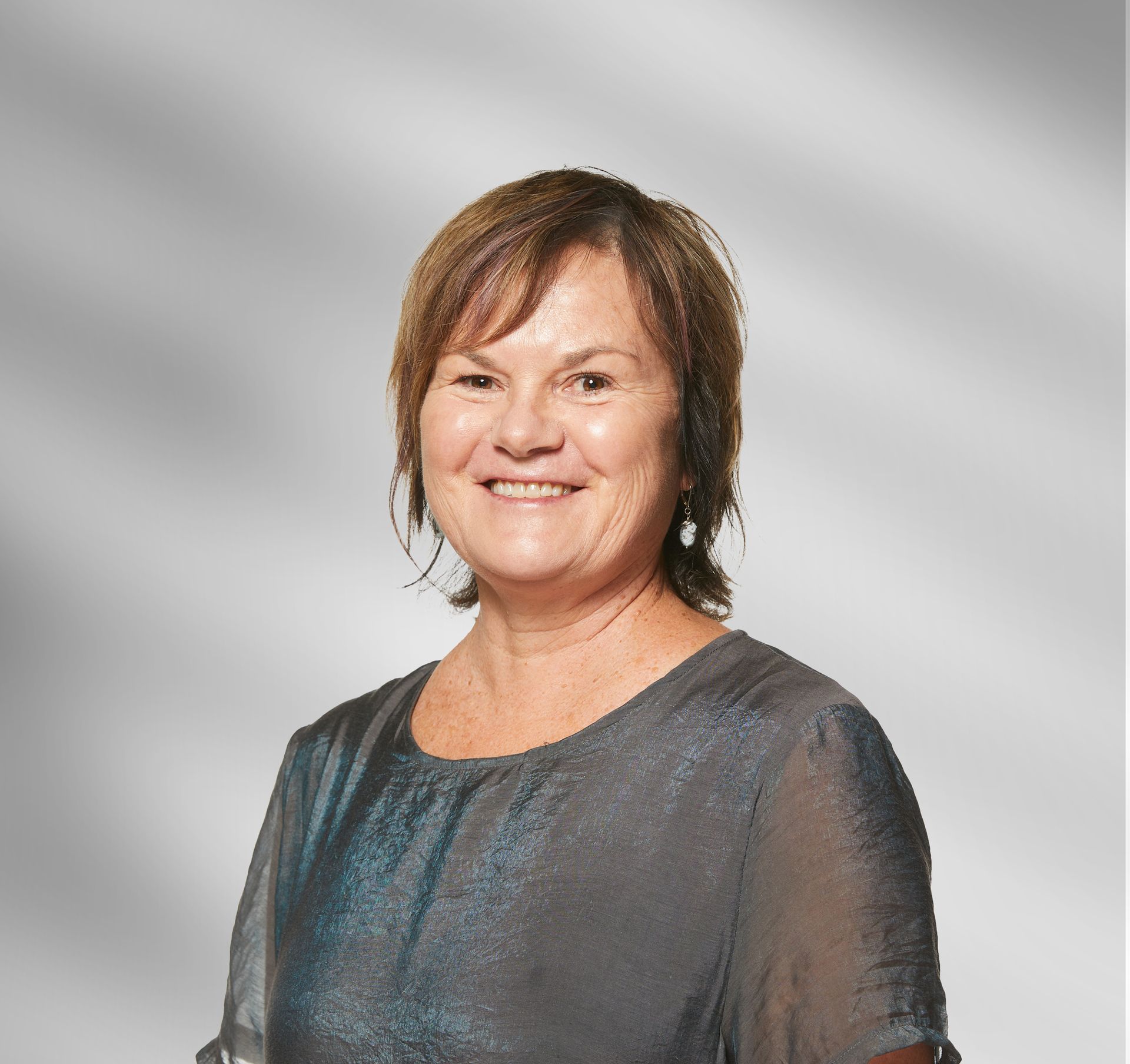 A woman in a gray shirt is smiling for the camera