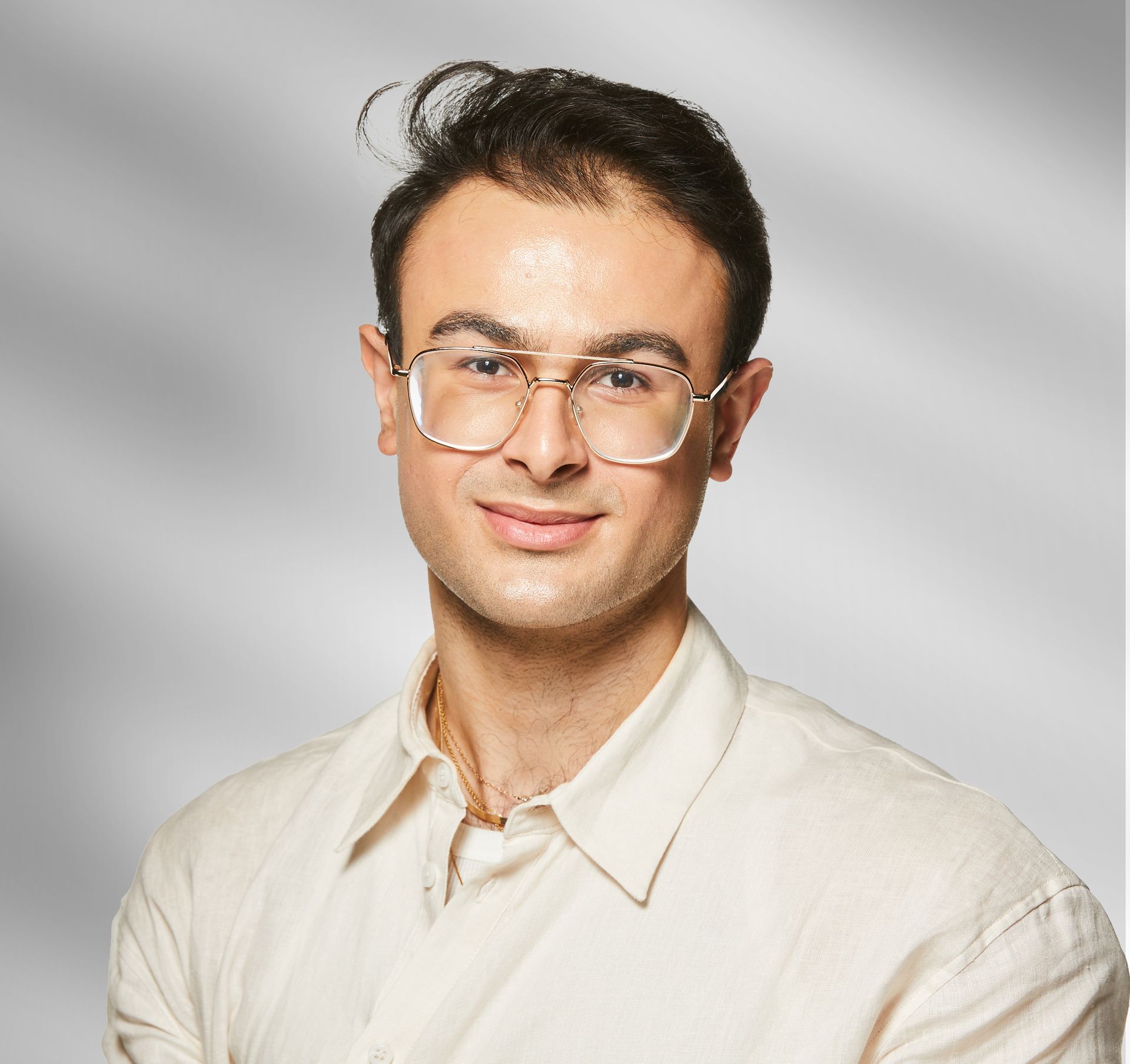 A man wearing glasses and a white shirt is smiling for the camera.