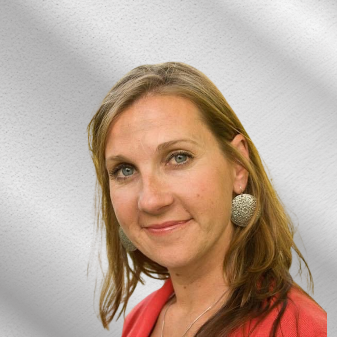A woman wearing a red jacket and silver earrings smiles for the camera