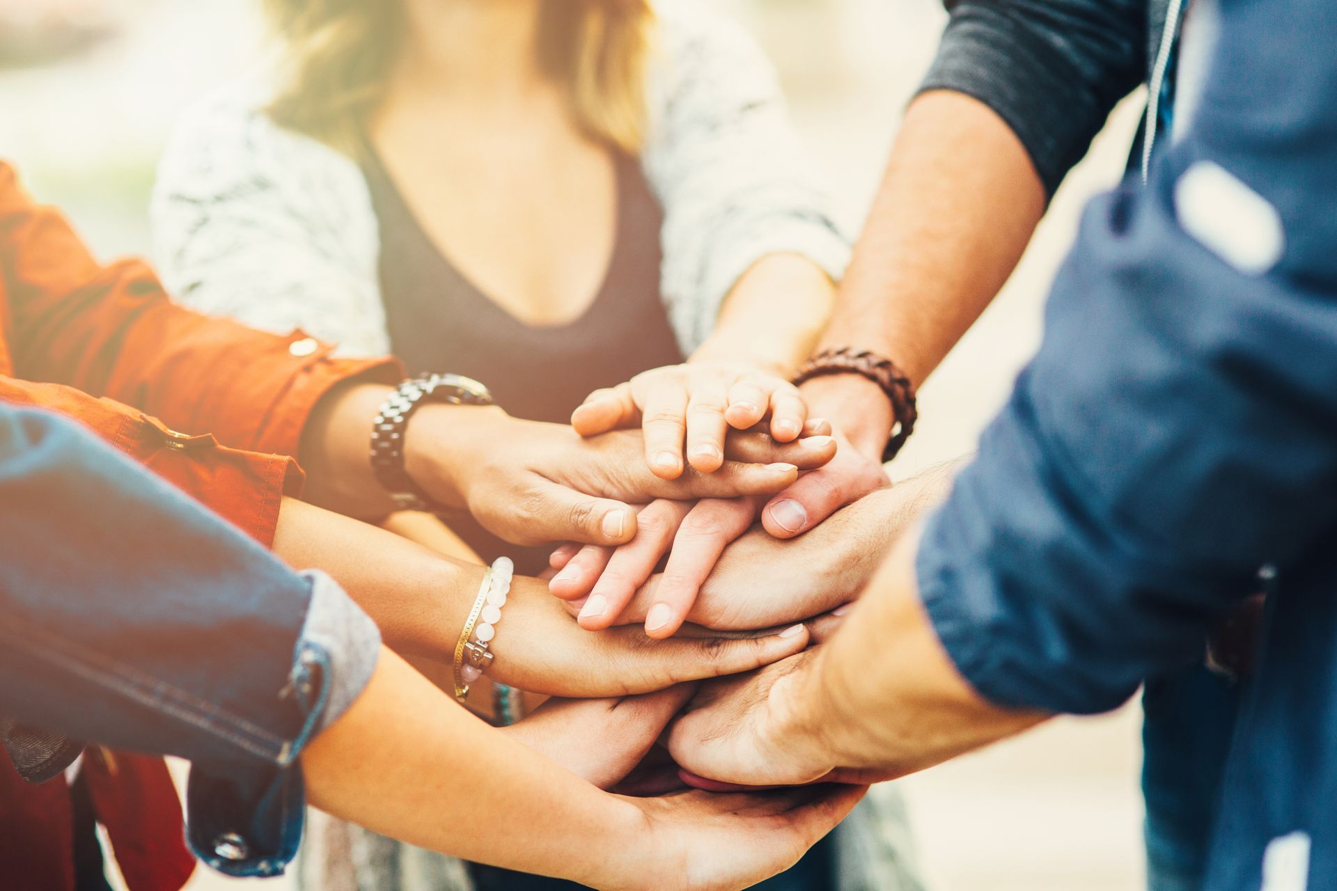 Group of people standing in a circle stacking hands.