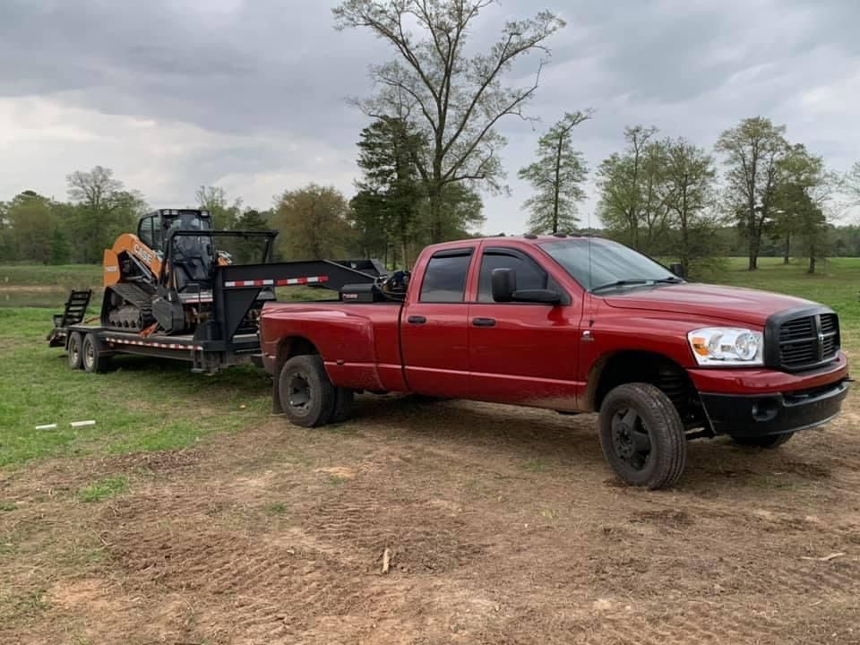A red truck is towing a trailer with a bulldozer on it.
