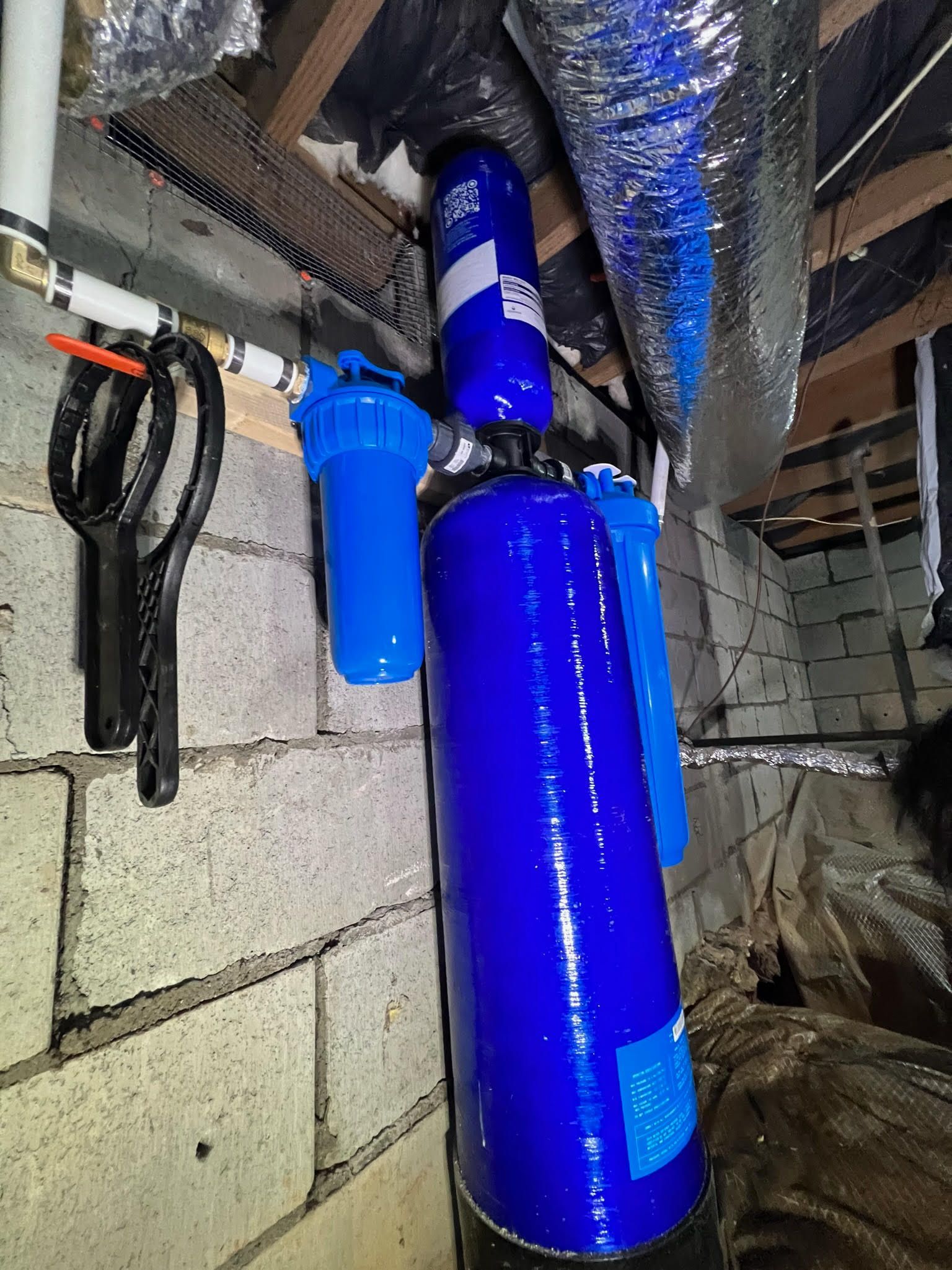 A blue pipe is hanging from the ceiling in a basement.