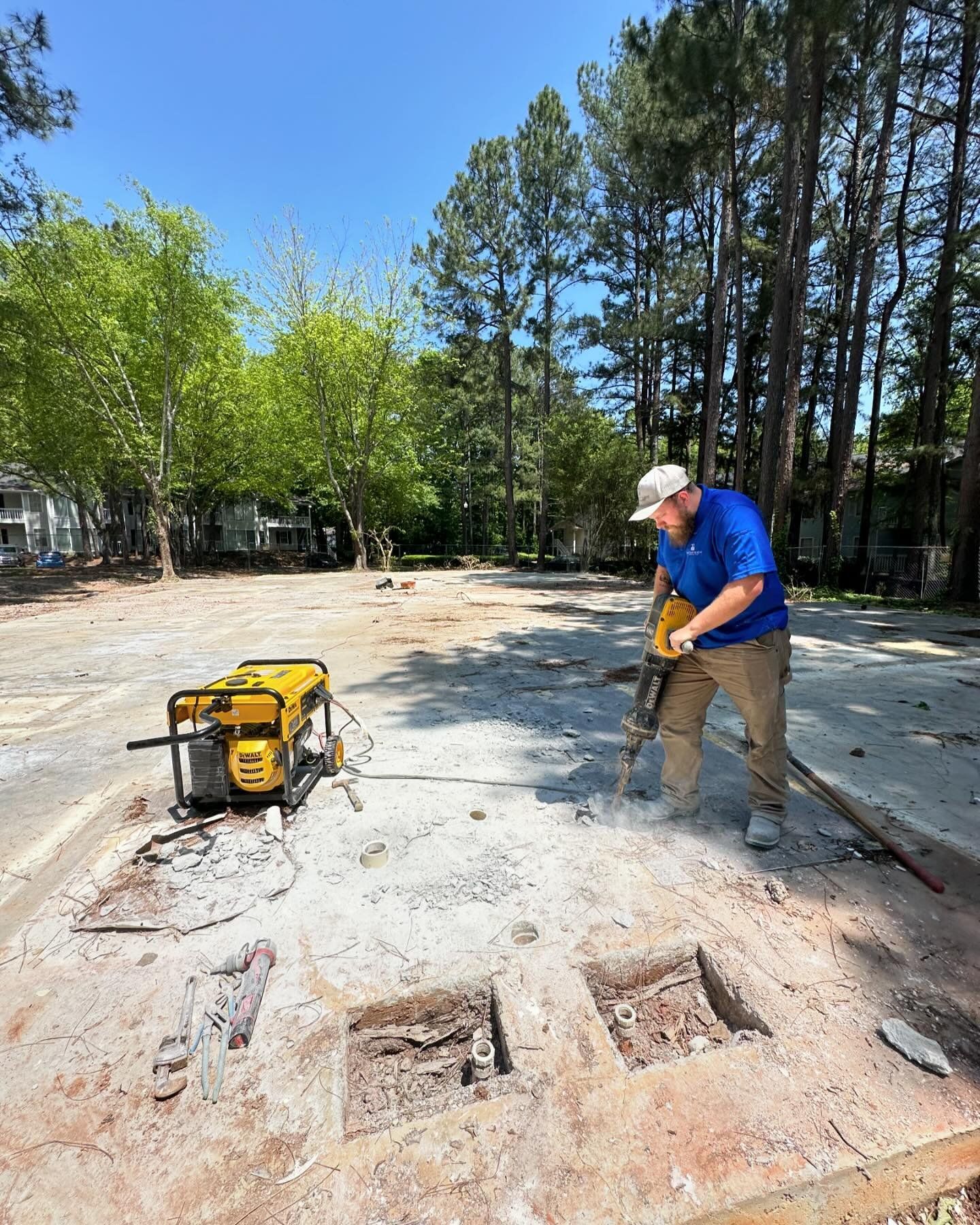 A man is using a hammer to break concrete in a parking lot.