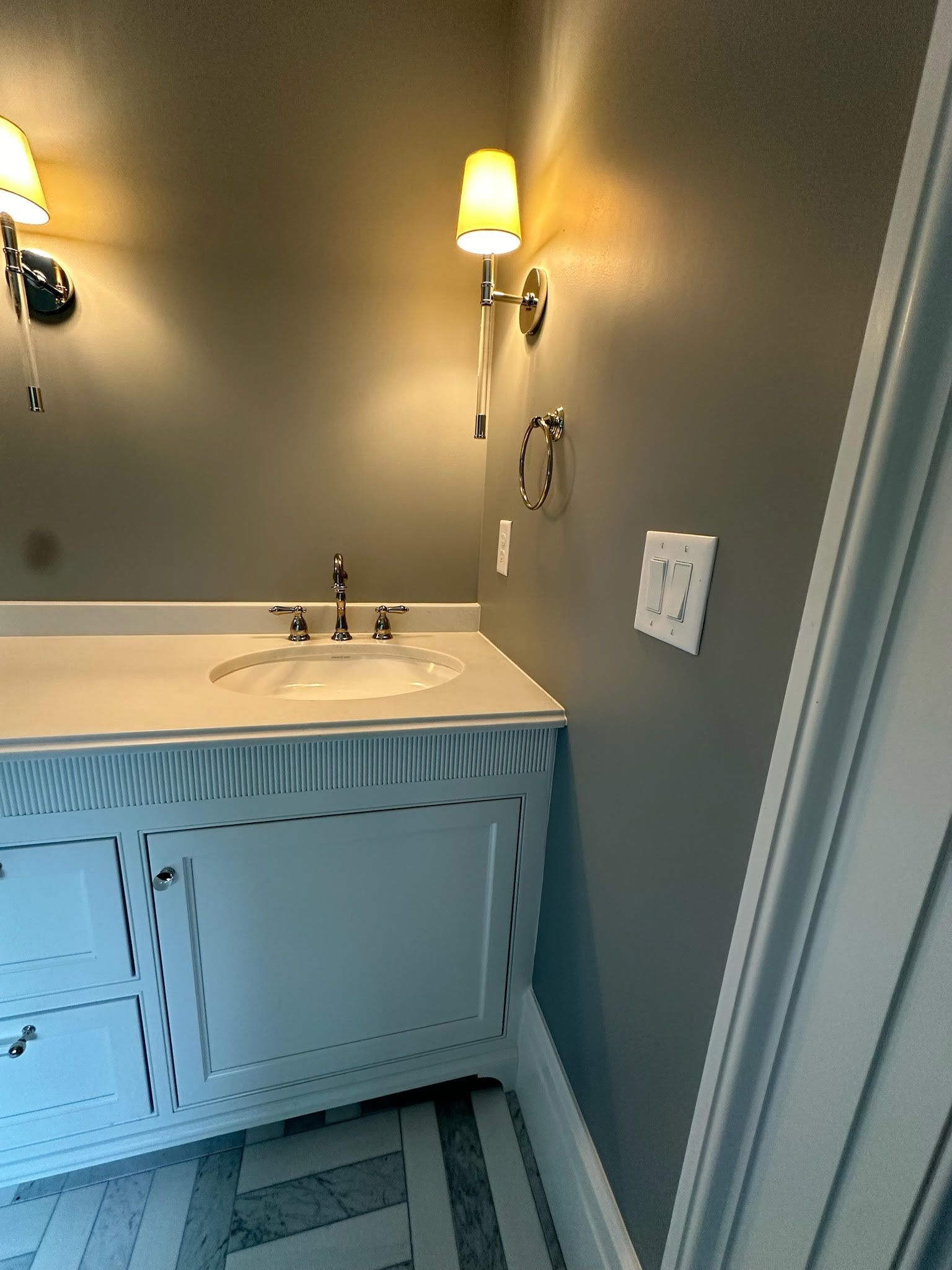 A bathroom with a sink and a light on the wall.