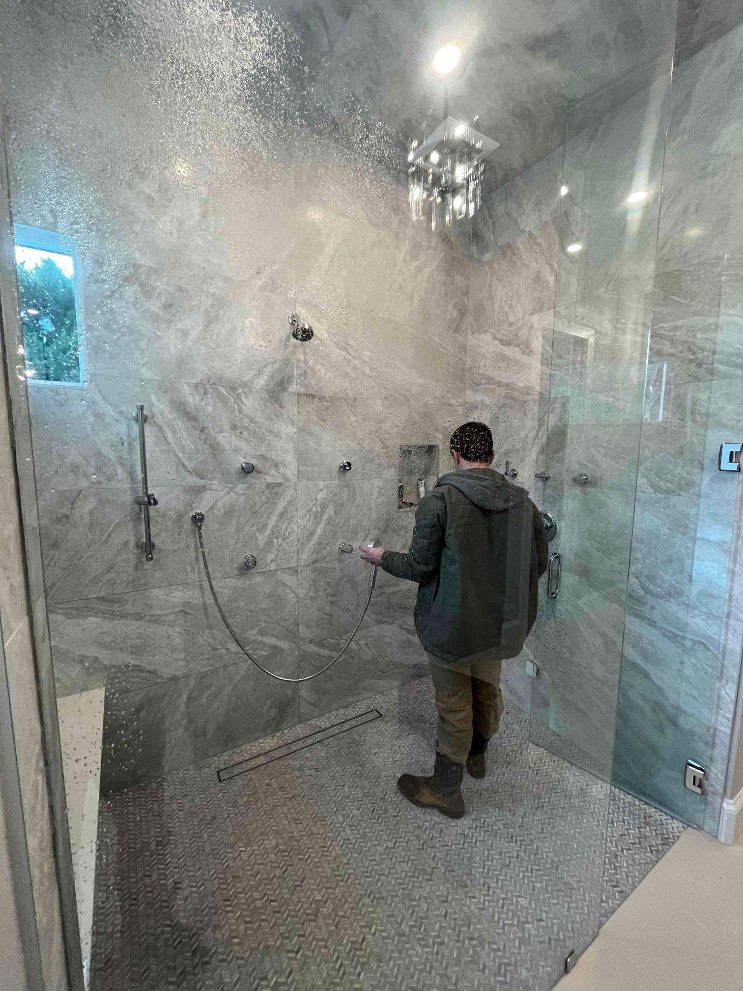 A man is standing in a shower with a lot of water coming out of it.