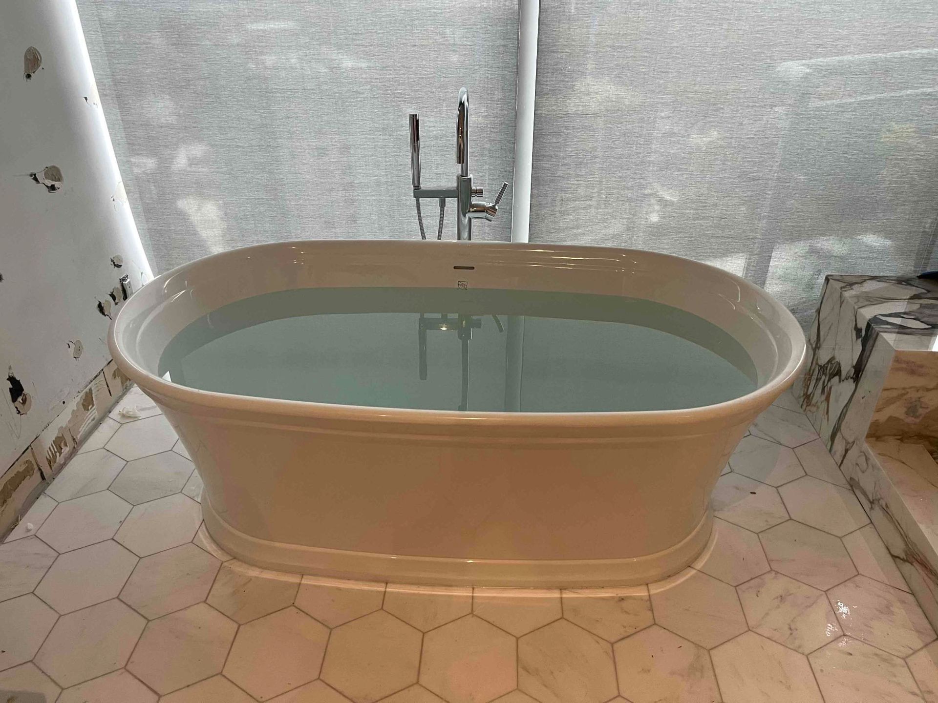 A white bathtub is filled with blue water in a bathroom.