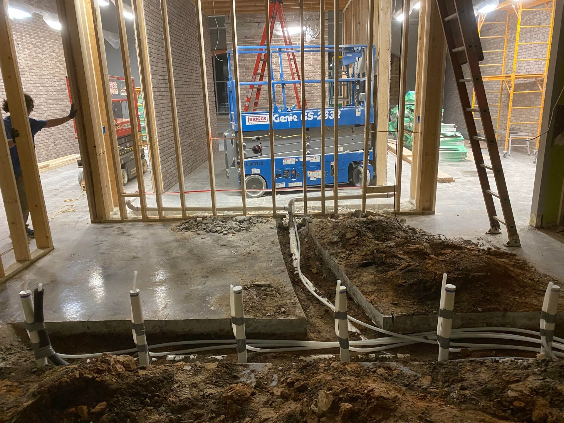 A man is standing in a room under construction with a ladder.
