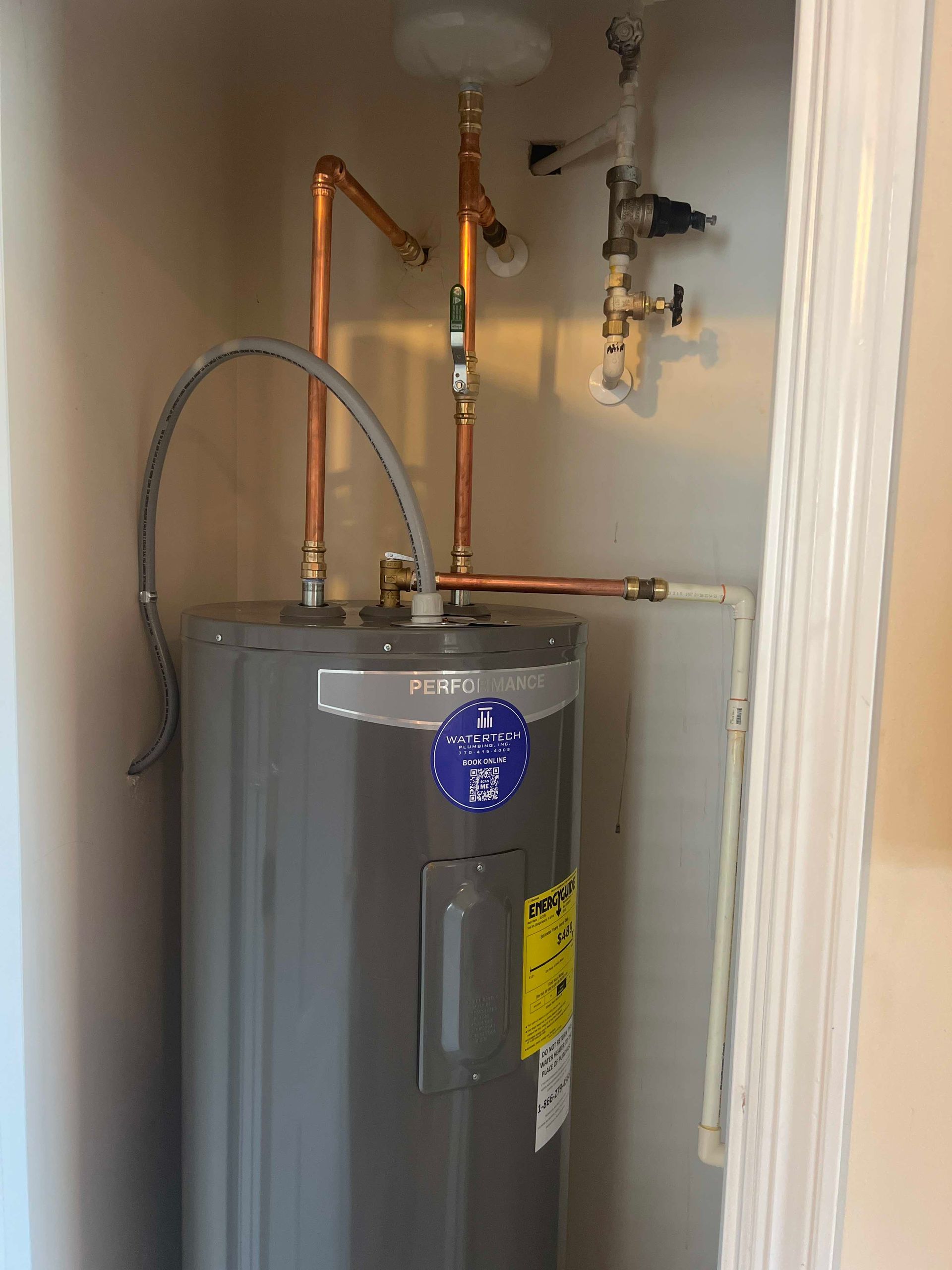 A water heater is sitting in a closet next to a door.