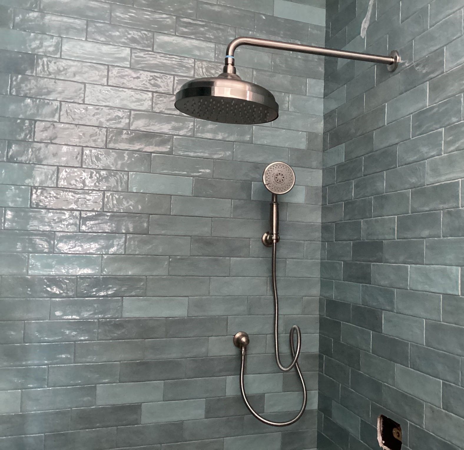 A shower head is attached to a brick wall in a bathroom