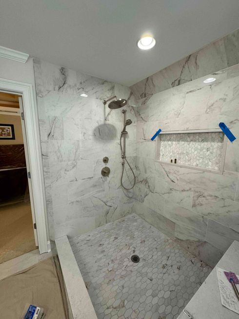 A bathroom with a walk in shower and a marble wall.