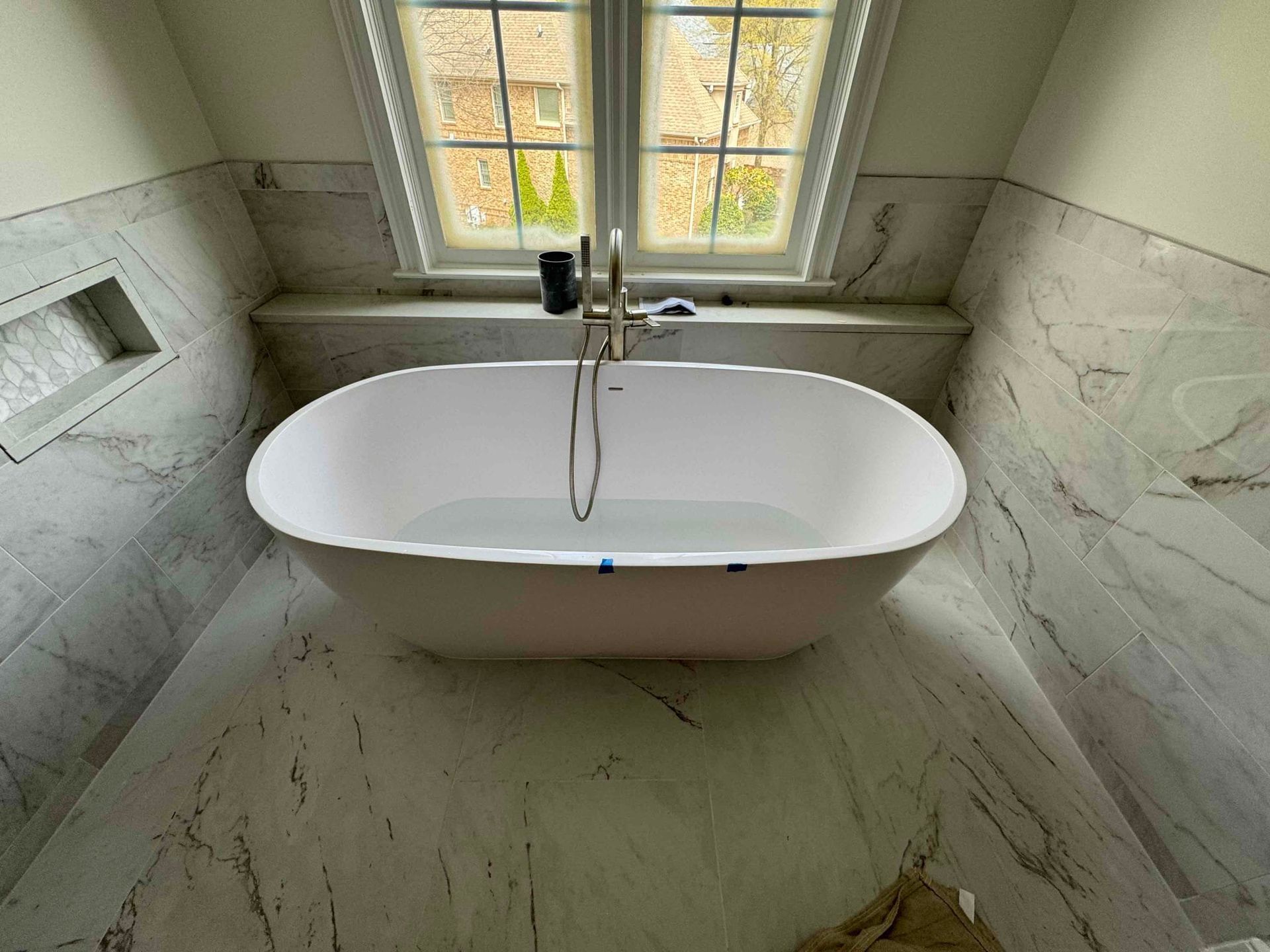 A bathtub is sitting in a bathroom next to a window.