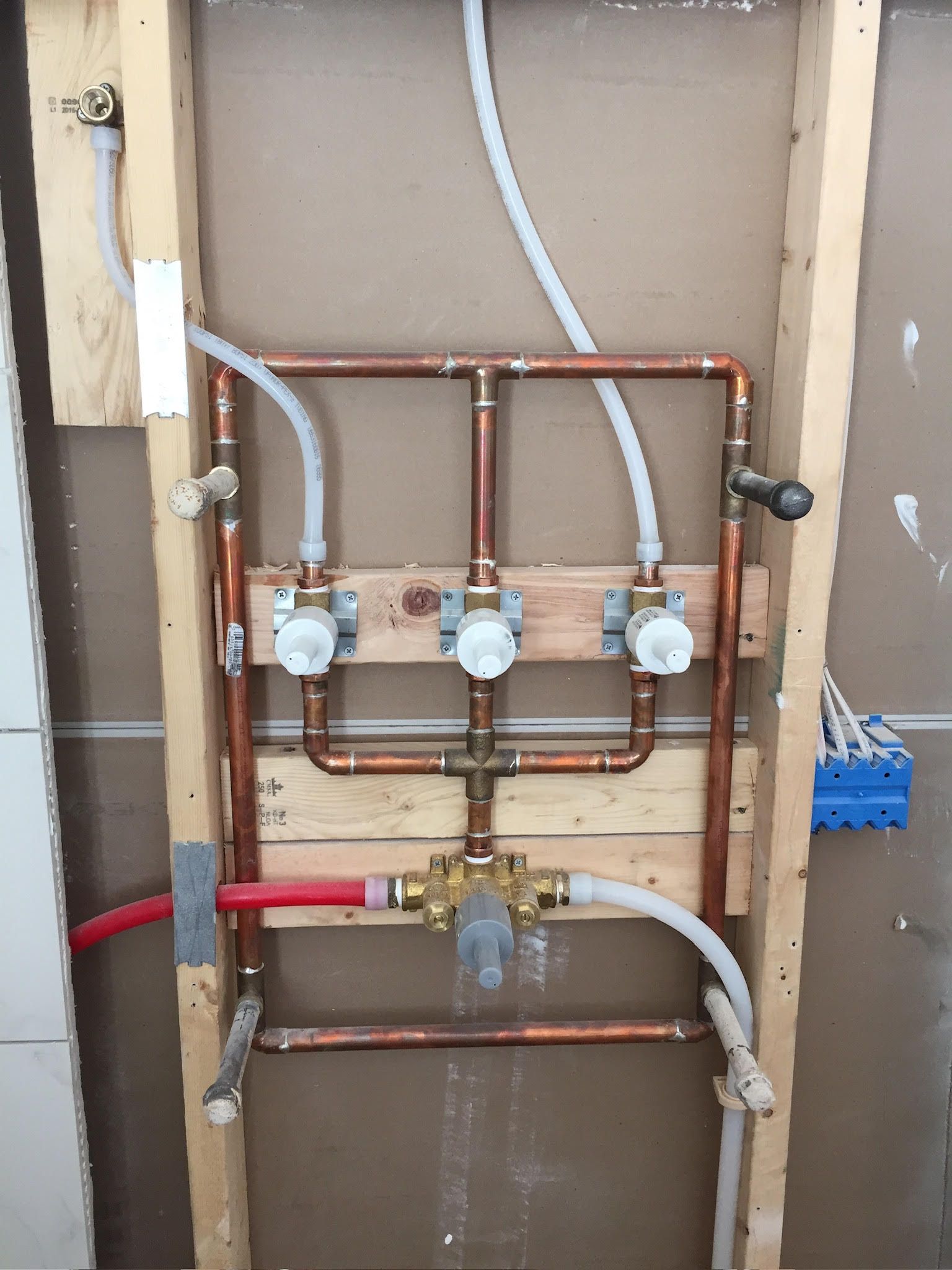 A wall with copper pipes and valves on it