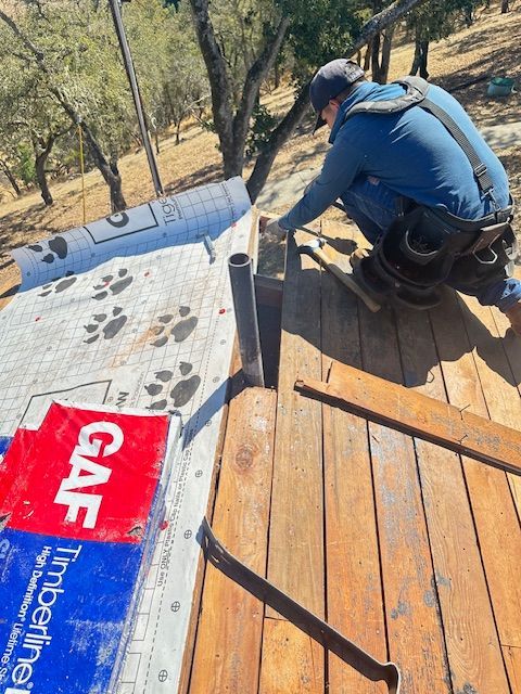 A Man Wearing Blue Is Working on a Roof — Novato, CA — Quevedo Roofing