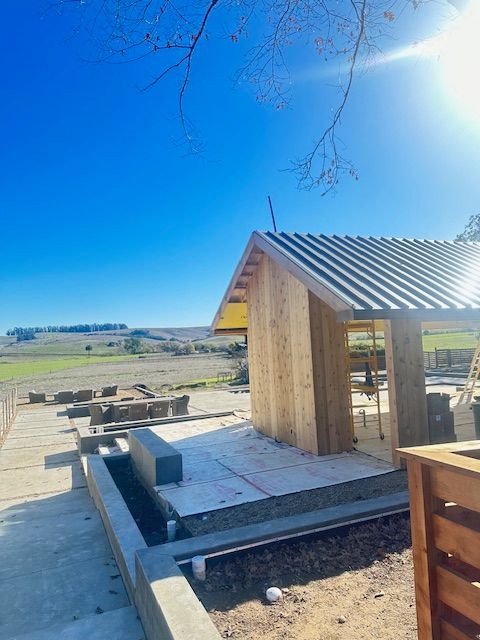 A small wooden house with a metal roof is being built.