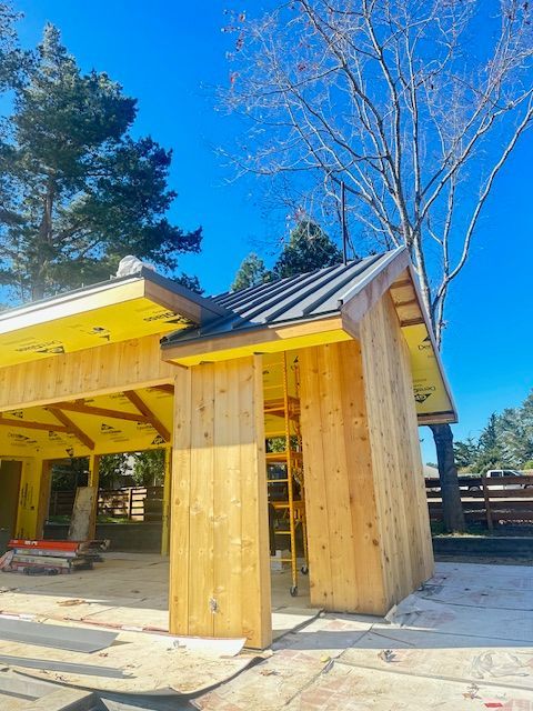 A wooden house is being built with a metal roof.