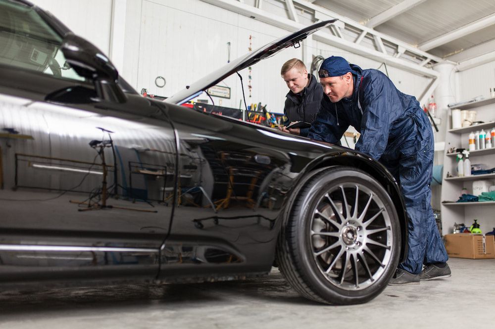 Two Mechanics Are Working On A Black Car In A Garage — A & D Automotive Technicians in Mackay, QLD
