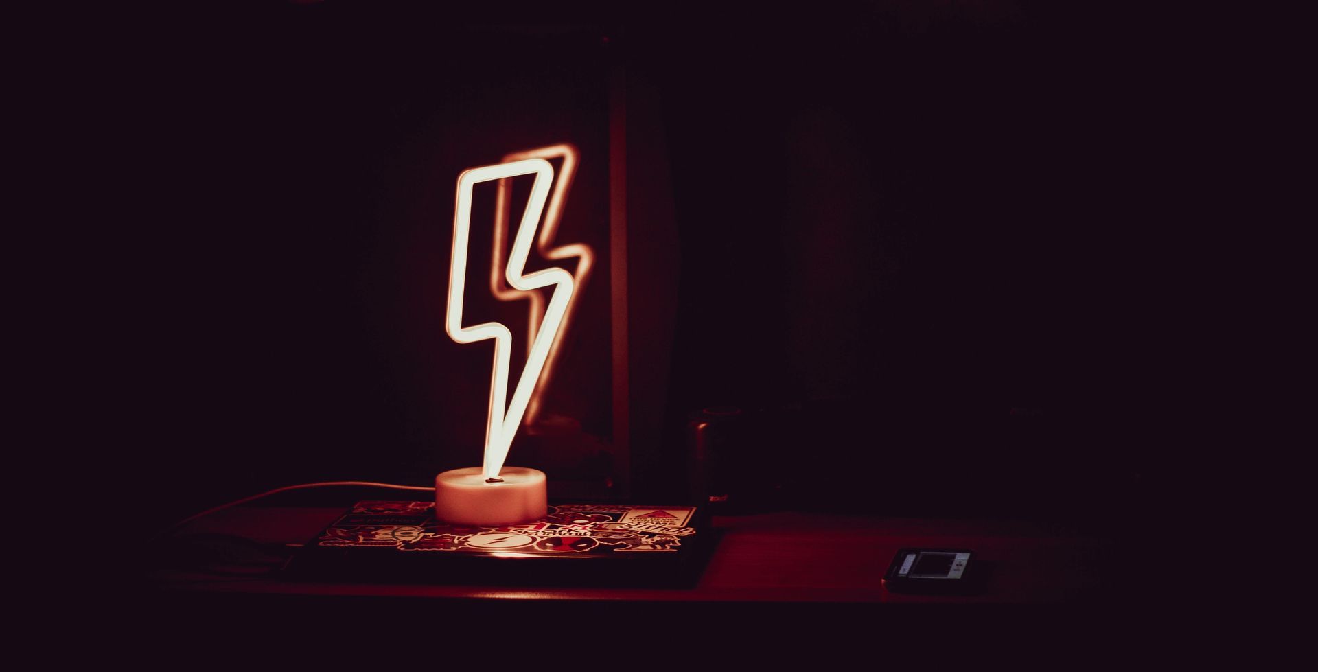 Neon lightning bolt glows on a dark surface.