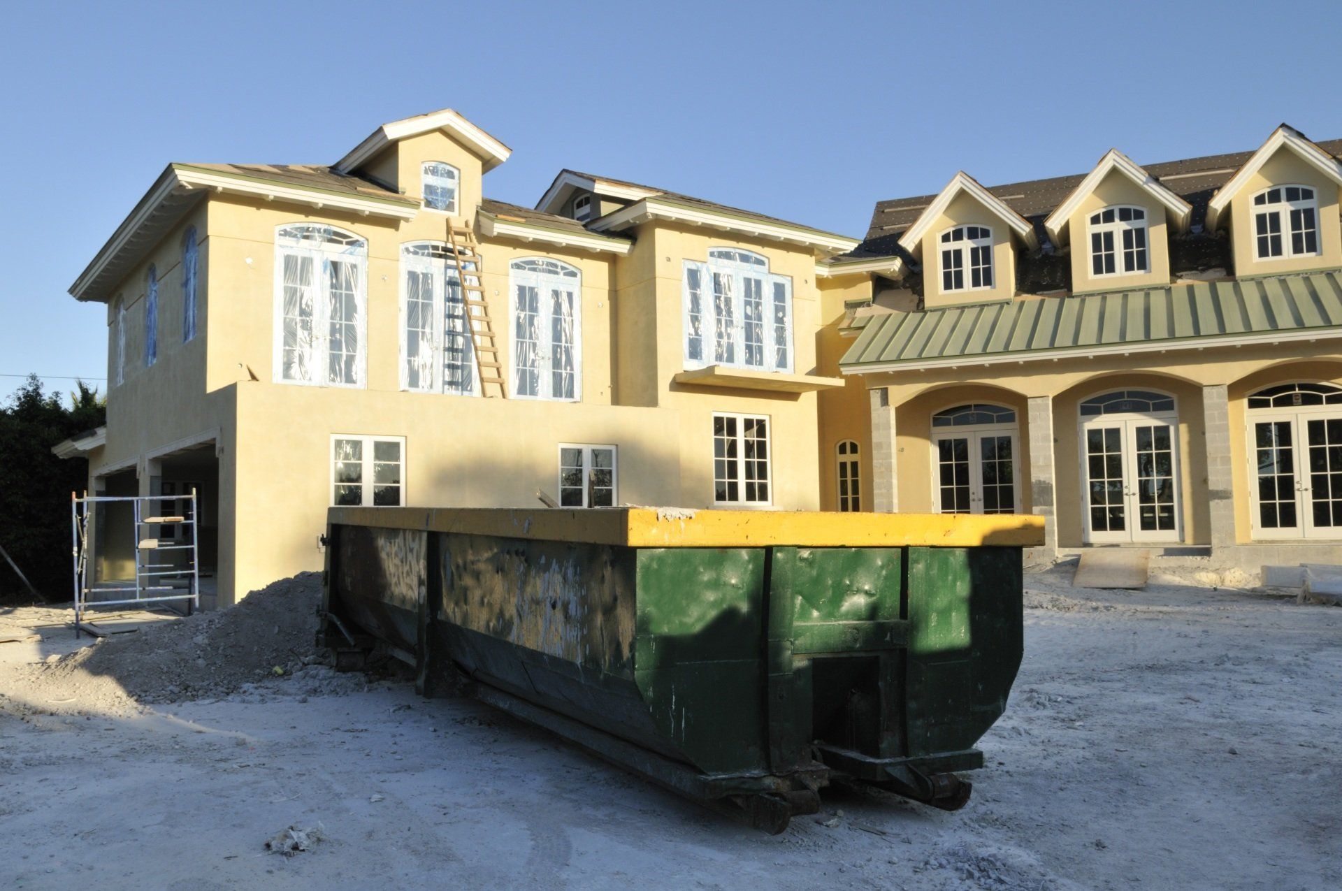 A large house under construction with a dumpster in front of it