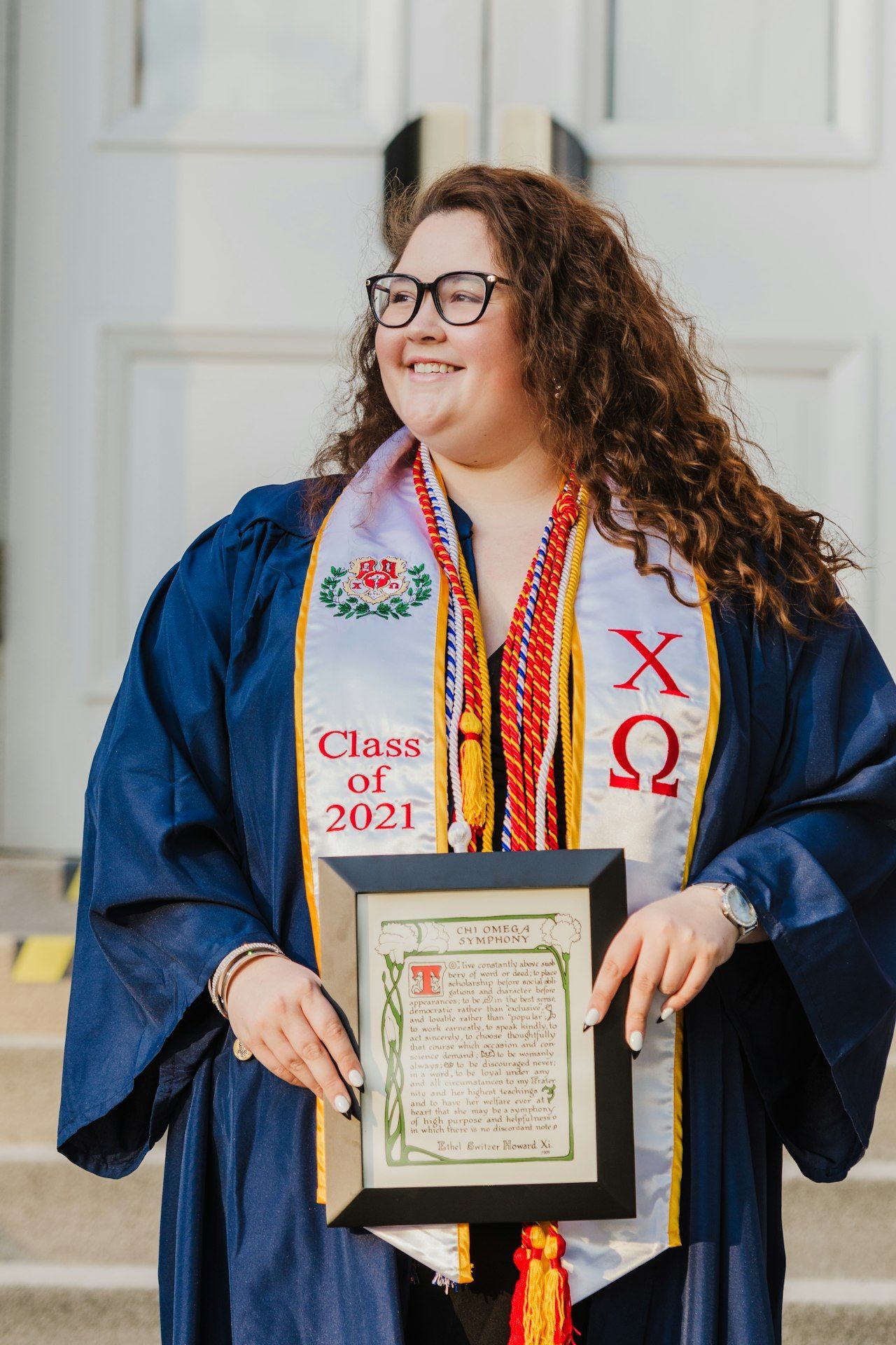 A woman in a graduation cap and gown is holding a framed certificate.