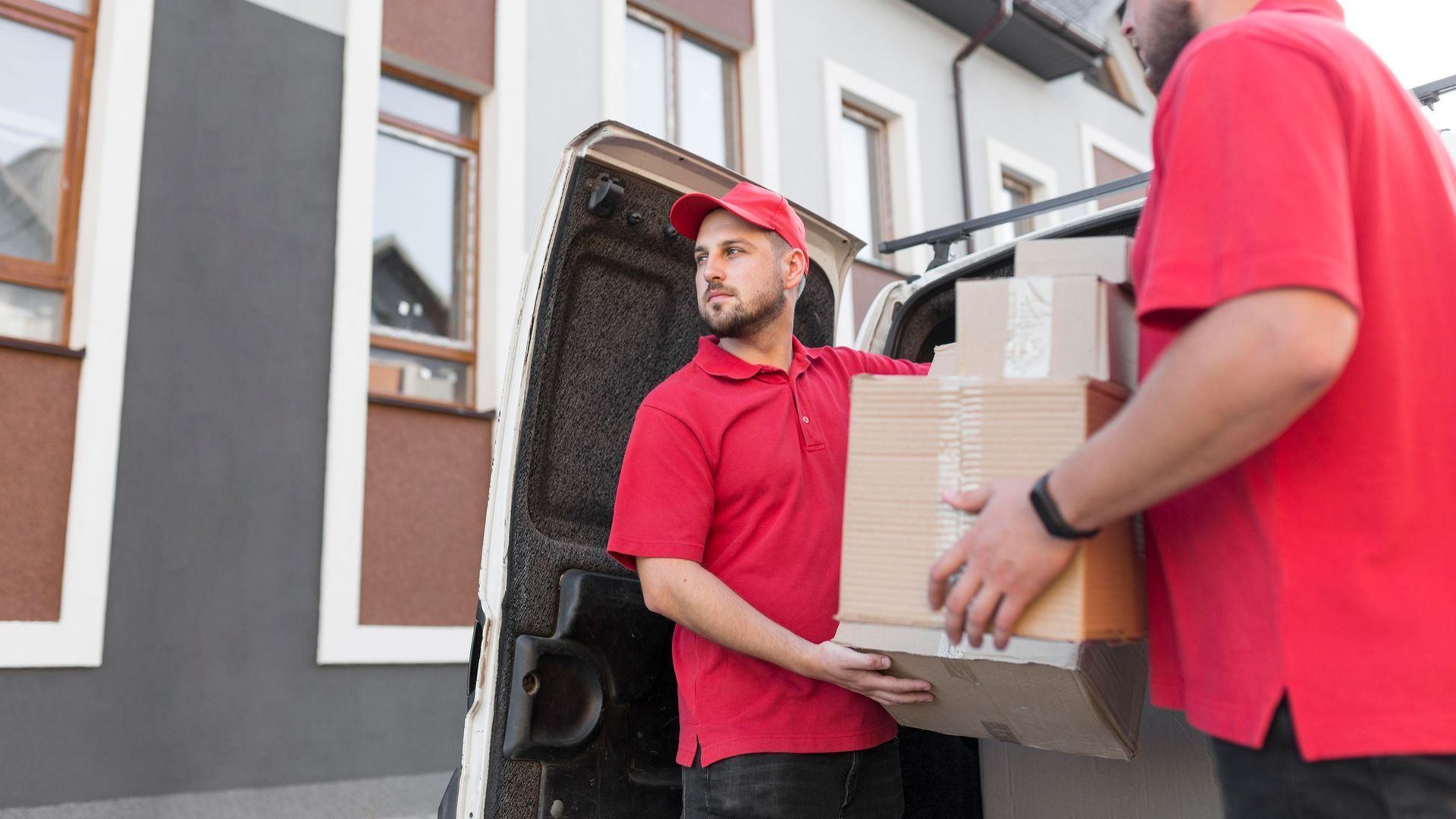 Two delivery men are loading boxes into a van.
