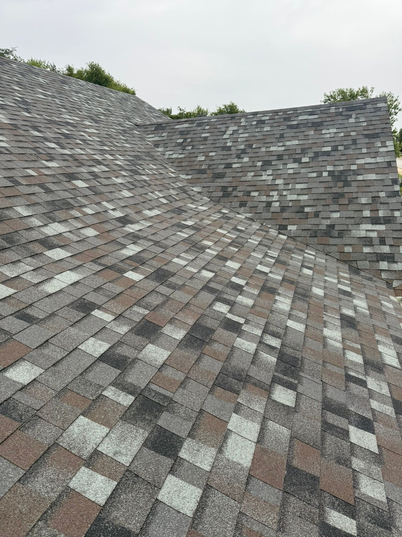 Close-up view of a multi-colored asphalt shingle roof, angled perspective.