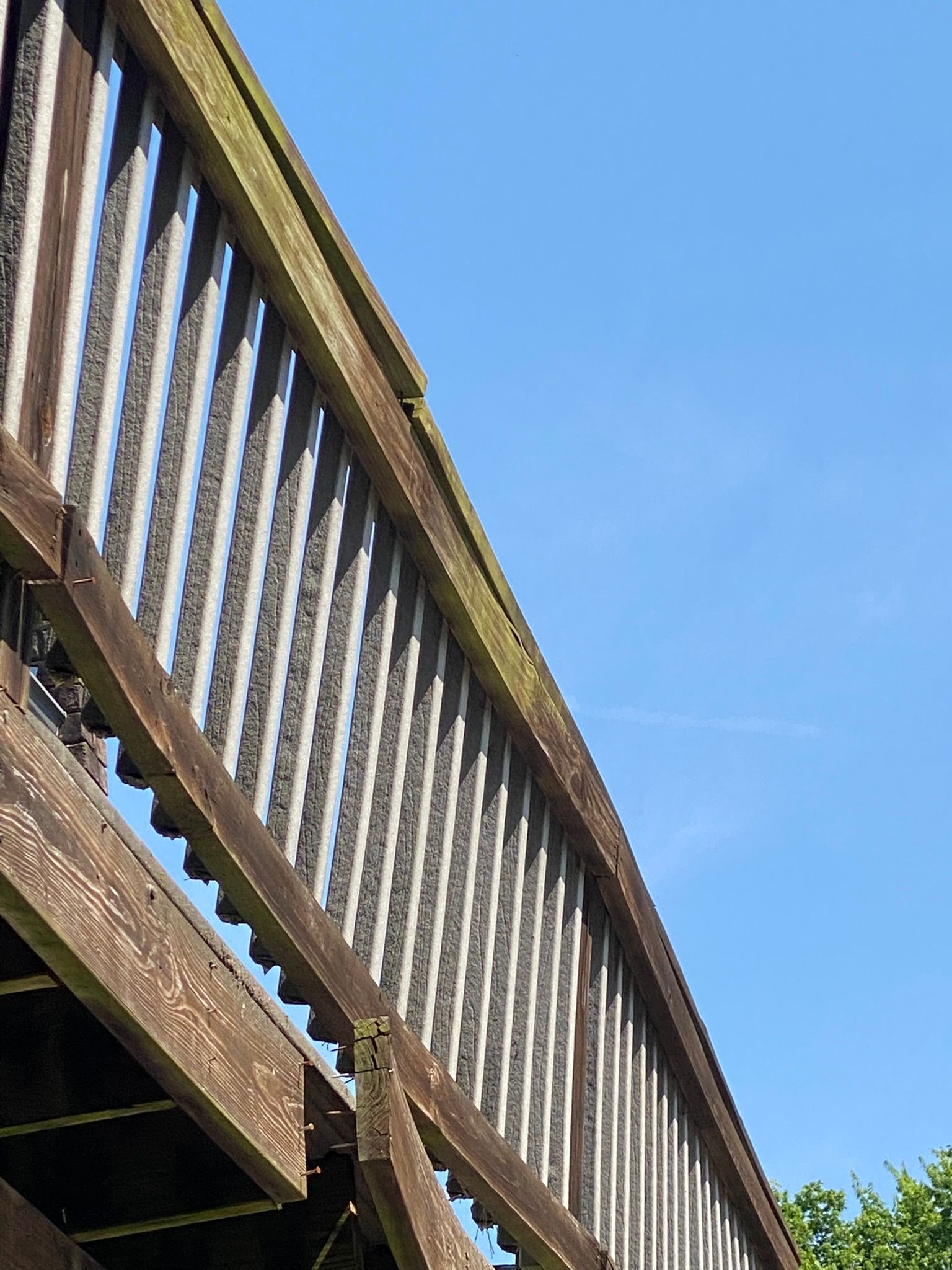 Wooden bridge railing against a blue sky.